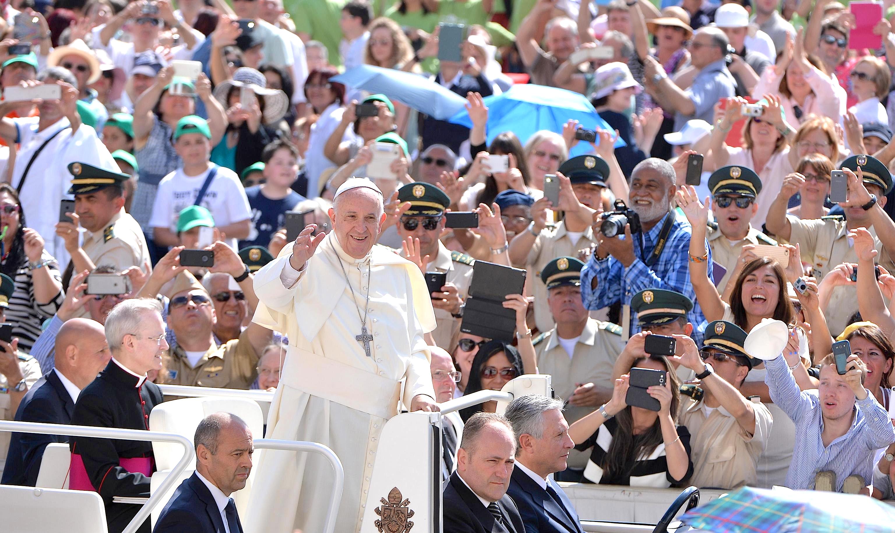 Pope Francis waves as he arrives for his weekly general audience