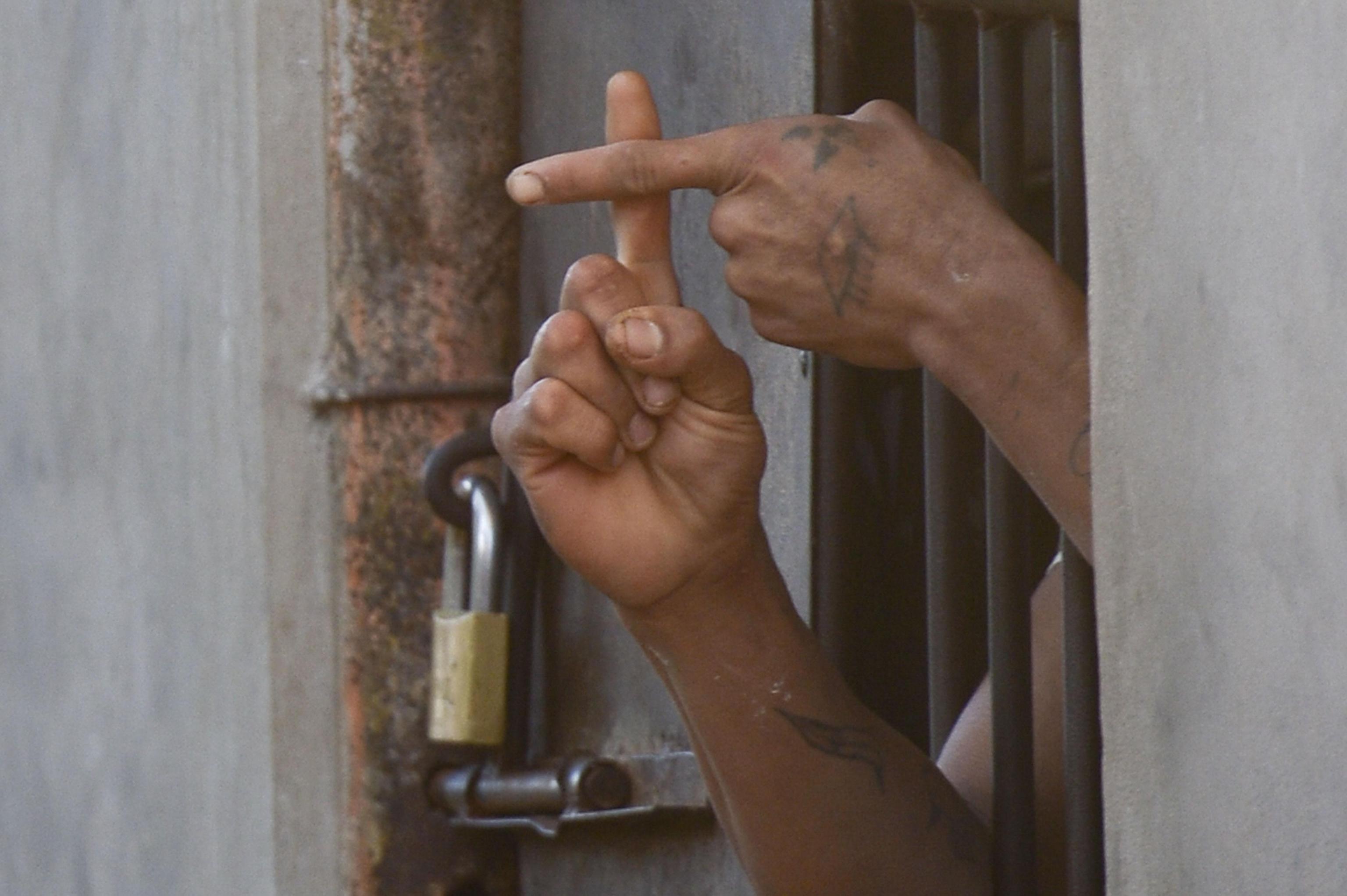 Inmate of the Reform Center of Santa Cruz-Palmasola forms the sign of the cross with his fingers