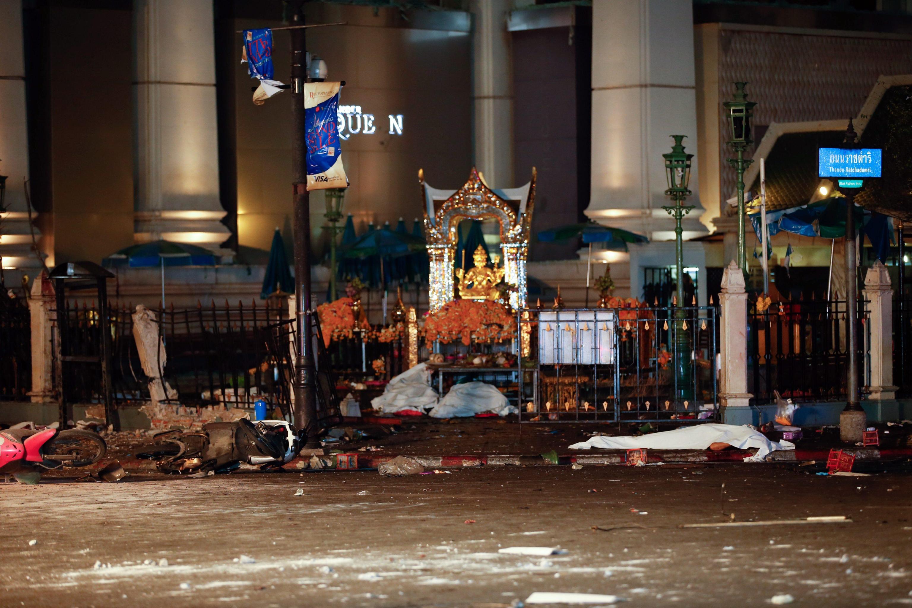 A body lies covered on the ground at the scene of a bomb attack near Erawan Shrine