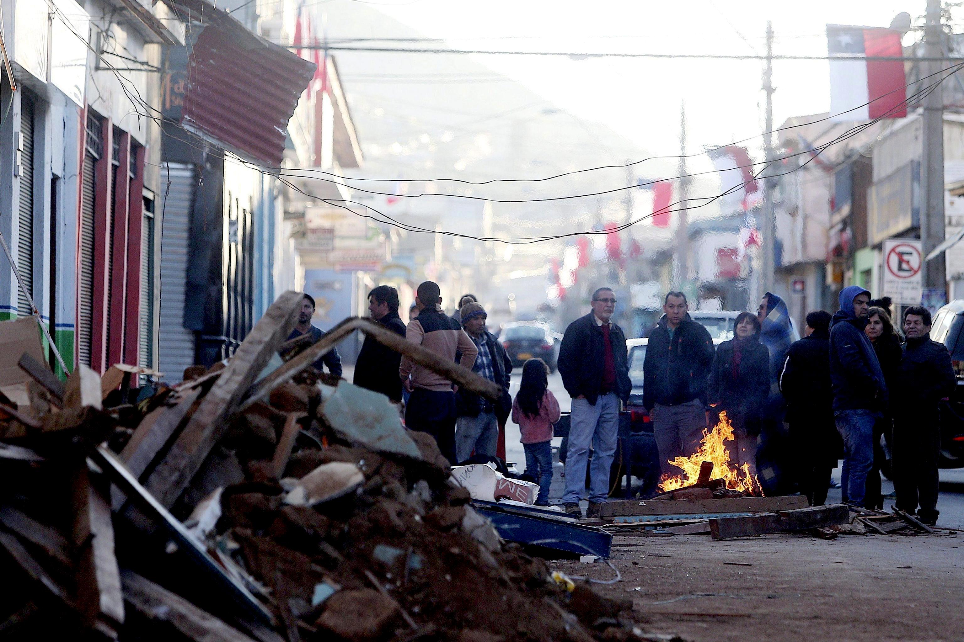Chileans stand around a fire on a road after being evacuated from their homes following an 8.3 Ritcher scale magnitude earthquake