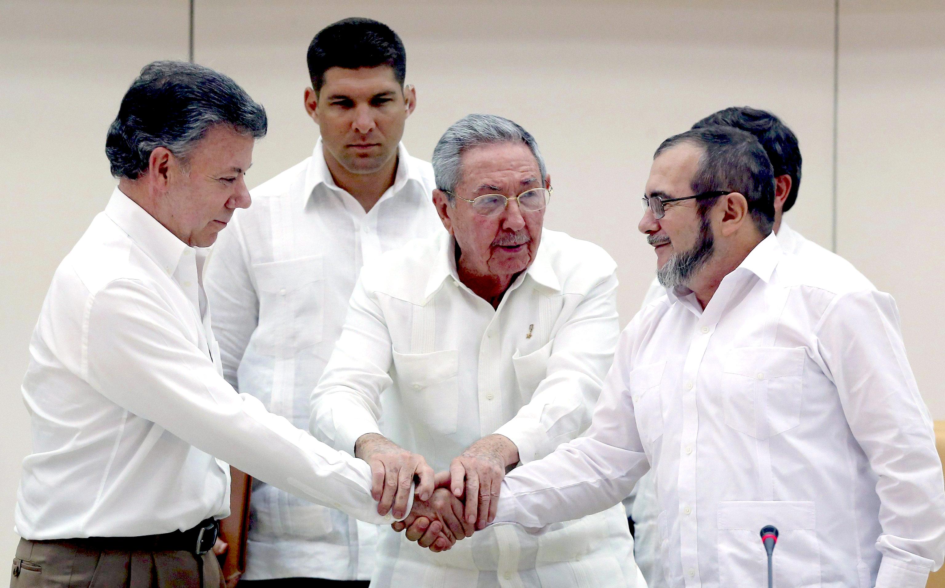 Cuban President Raul Castro (C) holds the hands of Colombian President Juan Manuel Santos (L) and top leader of the FARC