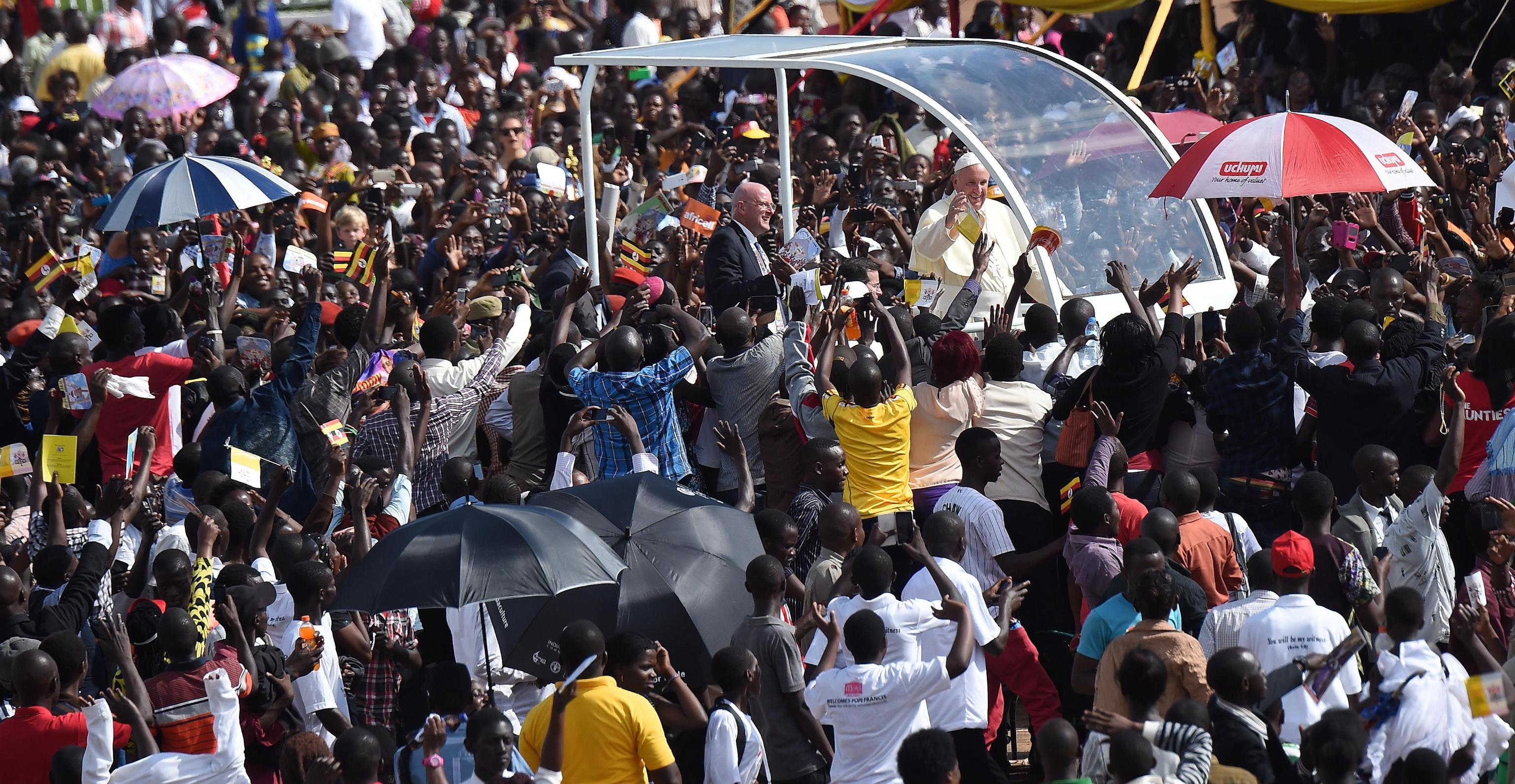 Pope Francis cheers the crowd from the popemobile at his arrival at the meeting with young people at the Kololo airstrip in Kampala