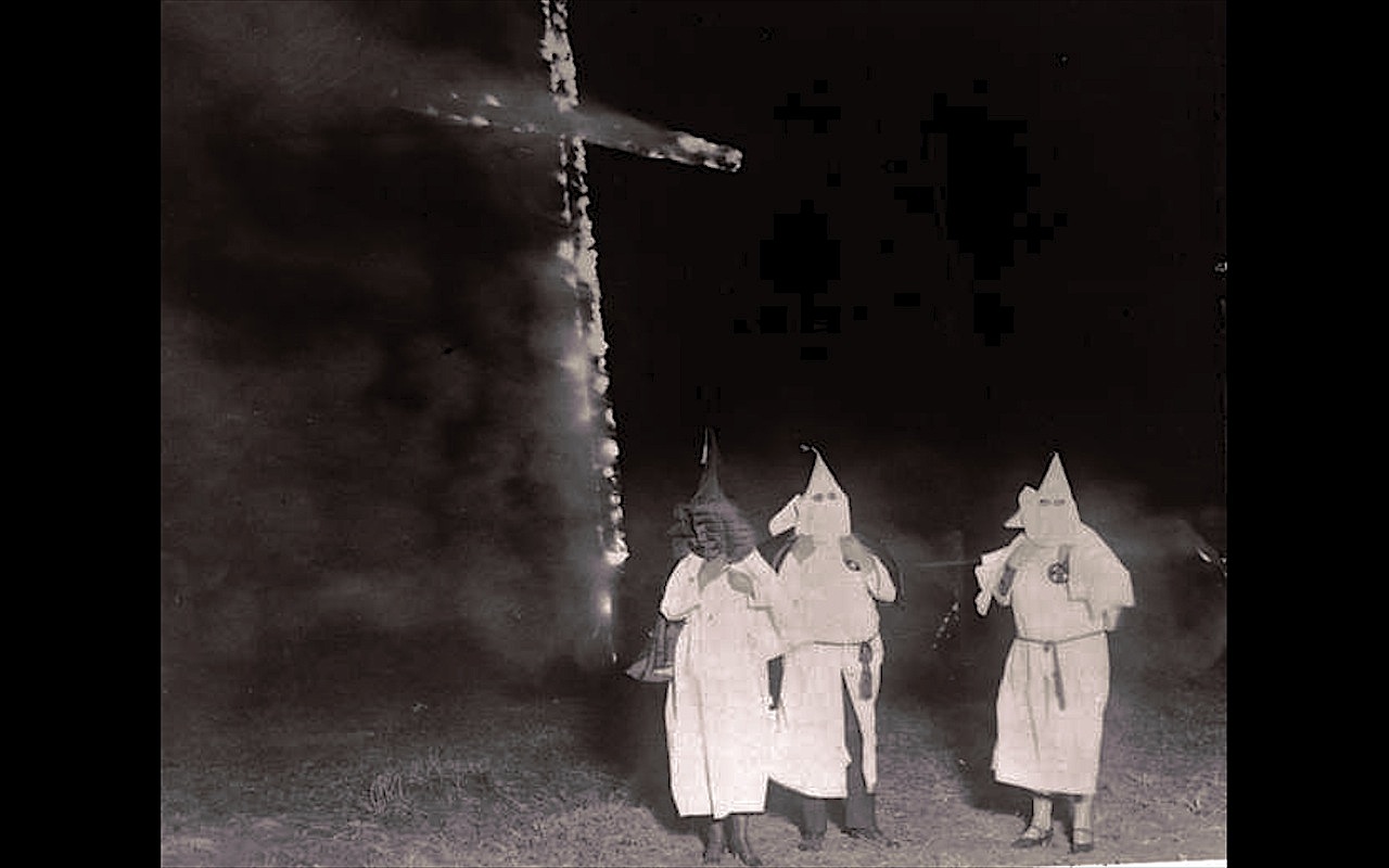 Ku Klux Klan members and a burning cross